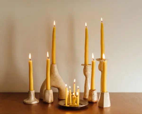 Velas amarillas de abeja en candelabros de cerámica. Una vela de palo santo para que sirve, ilumina el espacio con su suave resplandor.