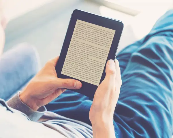 Osoba czyta książki na czytniku e-booków. Wygodny audiobook książki w cyfrowej formie.