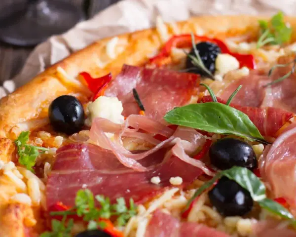 Pyszna pizza z cienko pokrojoną, aromatyczną szynką, czarnymi oliwkami i papryką. Idealna na każdą okazję!
