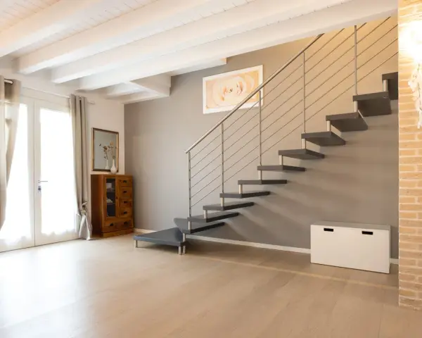Moderna scala a sbalzo, soluzione per chi ha una scala troppo ripida. Arredamento minimalista con mobili in legno e tessuti chiari.