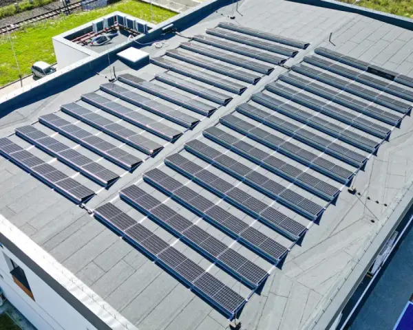 Duży dach płaski pokryty panelami fotowoltaicznymi, które zbierają energię słoneczną.