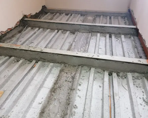 Prace nad tym, jak wzmocnić strop w starym domu. Widoczne belki stropowe i betonowanie.