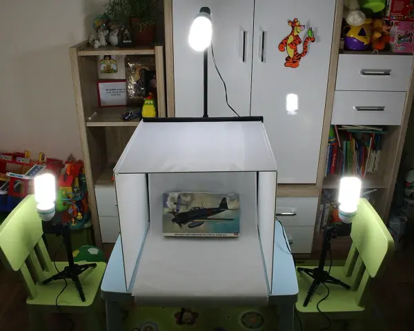 Domowy namiot bezcieniowy diy oświetla model samolotu. W tle regały z zabawkami i książkami.