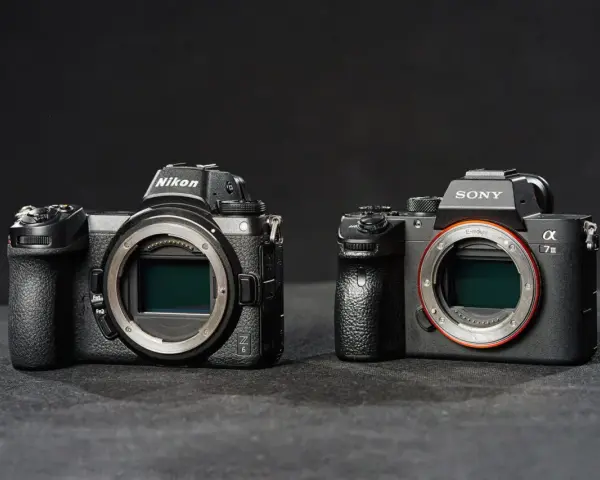 Dwie nowoczesne lustrzanki: Nikon z6 i Sony a7 III, stoją obok siebie na ciemnym tle.