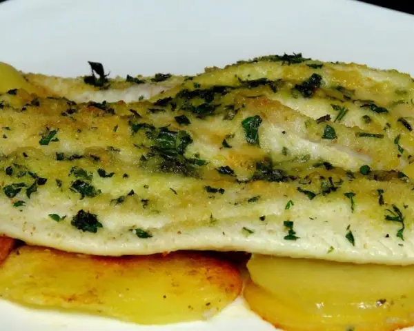 Delicioso lenguado al horno con patatas doradas y hierbas frescas.