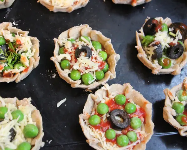 Mini pizze z groszkiem, oliwkami i serem, idealne na podwieczorek.