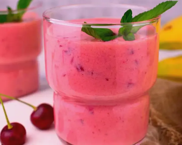 Różowy koktajl z bananów i wiśni, ozdobiony miętą. Idealny pomysł, co zrobić z bananów, gdy masz ochotę na coś pysznego.