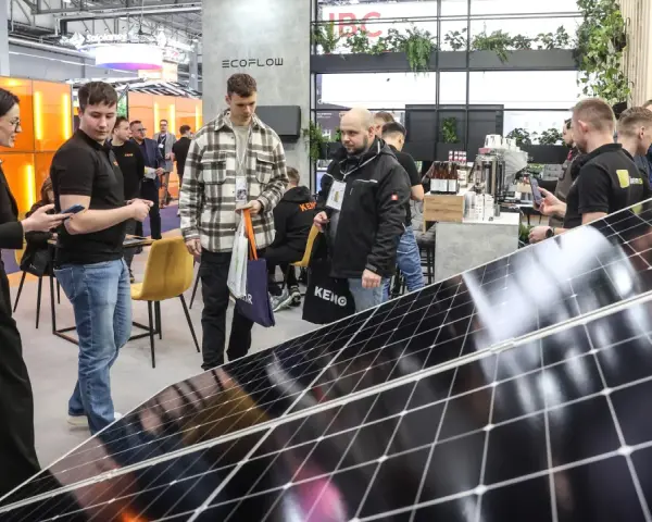 Ludzie zwiedzają targi energii odnawialnej, oglądając panele słoneczne i stoiska firm.