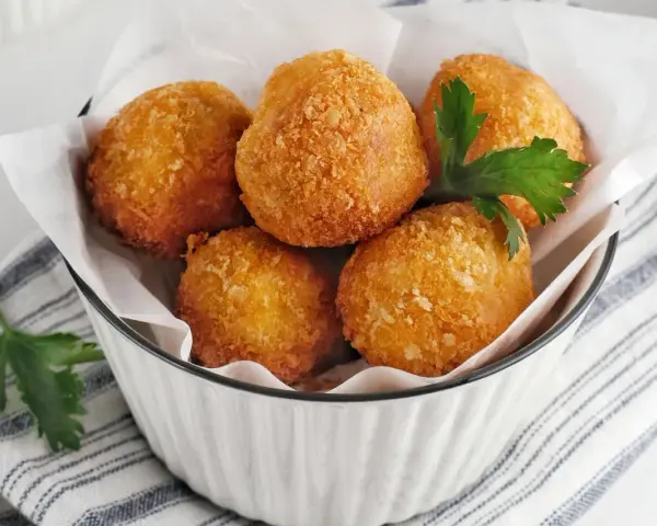 Knusprige Bitterballen, perfekt für ein leckeres Bitterballen Rezept. Serviert in einer Schüssel mit Petersilie.