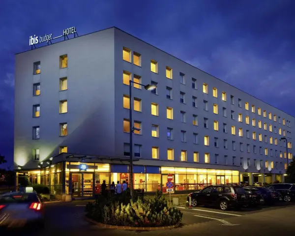 Ibis Budget Warszawa Centrum nocą. Hotel z podświetlanym logo, oknami i parkingiem.