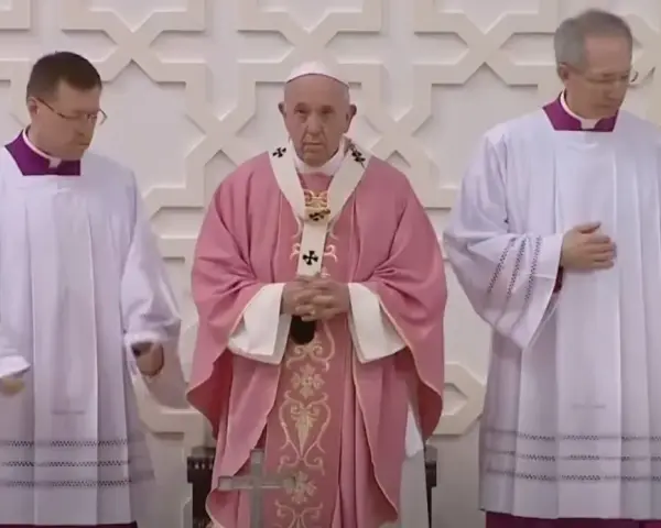 Pope Francis, in a pink vestment for the fourth Sunday of Lent, stands between two clergy members in white albs.