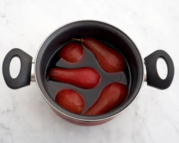 Olla con peras al vino tintas, listas para ser un postre delicioso.