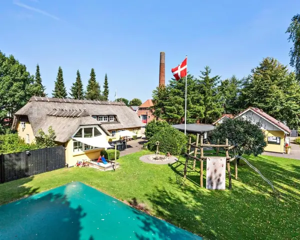 En idyllisk campingplats i Billund med halmtak, lekplats och danska flaggan vajande stolt.