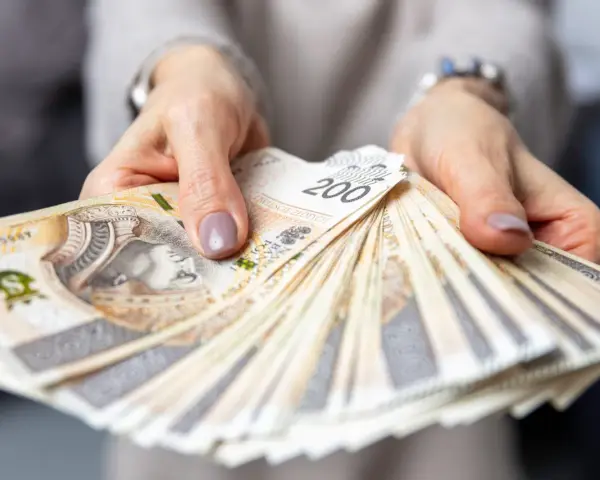 Dłonie trzymające plik banknotów 200 zł. Pytanie o to, ile zarabia hotelarz, często wiąże się z takimi widokami.