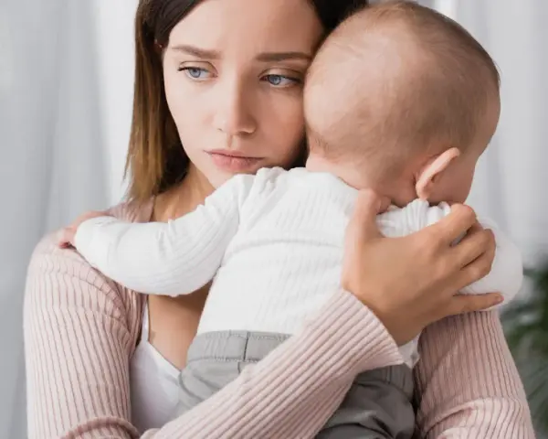 Traurige Mutter hält ihr Baby. Ihre Augen spiegeln eine tiefe Enttäuschung wider, vielleicht gender disappointment.