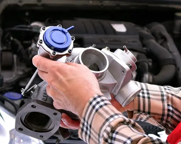 Mechanik pokazuje turbosprężarkę, element silnika, gdzie znajduje się czujnik ciśnienia doładowania.