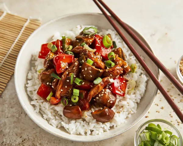 Schüssel mit Reis und einem köstlichen Chicken Teriyaki, garniert mit Frühlingszwiebeln und Sesam.