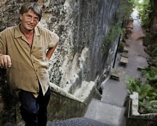 Mike Oldfield, znany muzyk, stoi na kamiennych schodach. Może to miejsce, gdzie mieszkał z żoną.