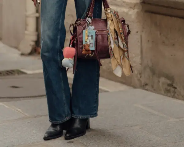 Botas negras elegantes con tacón, perfectas para complementar unos pantalones vaqueros anchos y un bolso de cuero con adornos.