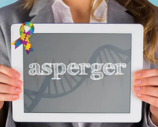 Kolorowa wstążka symbolizuje świadomość autyzmu. Na tablecie widnieje napis "asperger", a w tle grafika DNA, nawiązująca do objawów Aspergera.