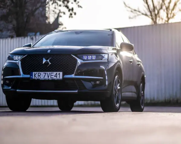 Czarny DS 7 Crossback z silnikiem 1.6 PureTech, z przodu, z niebieskimi światłami LED, na tle ogrodzenia.