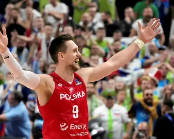 Bartosz Szczepanik w koszulce z numerem 9, z podniesionymi rękami, świętuje zwycięstwo na tle rozentuzjazmowanych kibiców.