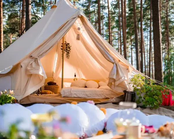 Przytulny namiot w lesie, idealny na glamping w Polsce. Wygodne łóżko, dekoracje i otoczenie natury tworzą magiczną atmosferę.