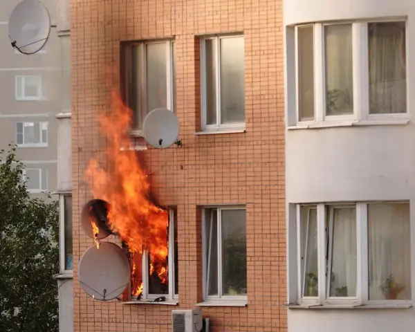 Flammen schlagen aus einem Fenster eines Mehrfamilienhauses. Ein trauriger Anblick, besonders wenn man bedenkt, dass es sich um einen wohnungsbrand ohne hausratversicherung handelt.