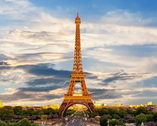 Le symbole de la Tour Eiffel se dresse fièrement sous un ciel nuageux, illuminé par les rayons du soleil couchant.