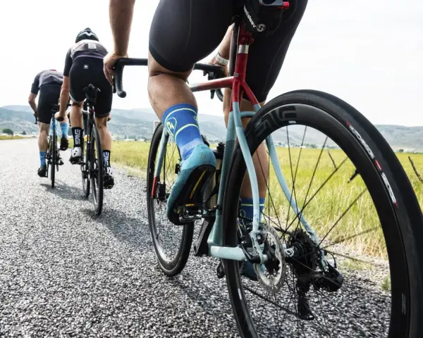 Cyclists on an endurance bike vs road bike race down a gravel road, showcasing their gear and determination.