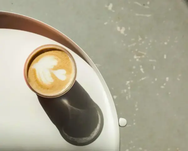 Idealna kawa flat white z pianką w kształcie liścia, podana na tacy.