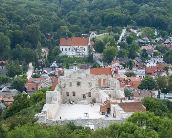 Ruiny zamku w Kazimierzu Dolnym na tle zielonych wzgórz i zabudowań.