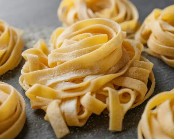 Nidi di tagliatelle fatte in casa, spolverate di farina, pronte per essere cucinate.