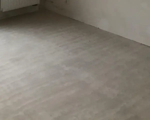 Świeżo wylana, szara krzywa wylewka samopoziomująca na podłodze, gotowa na dalsze prace wykończeniowe.