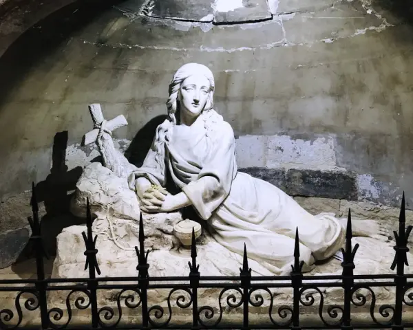 Sculpture of Mary Magdalene in repose, near a cross, possibly at her burial site.