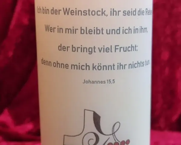 Der Text auf der Kerze zitiert Johannes 15,5: "Ich bin der Weinstock, ihr seid die Rebe. Wer in mir bleibt und ich in ihm, der bringt viel Frucht; denn ohne mich könnt ihr nichts tun.