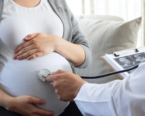 Lekarz osłuchuje brzuch ciężarnej, analizując wyniki badań USG. W trosce o zdrowie dziecka, wyklucza się m.in. cytomegalię.