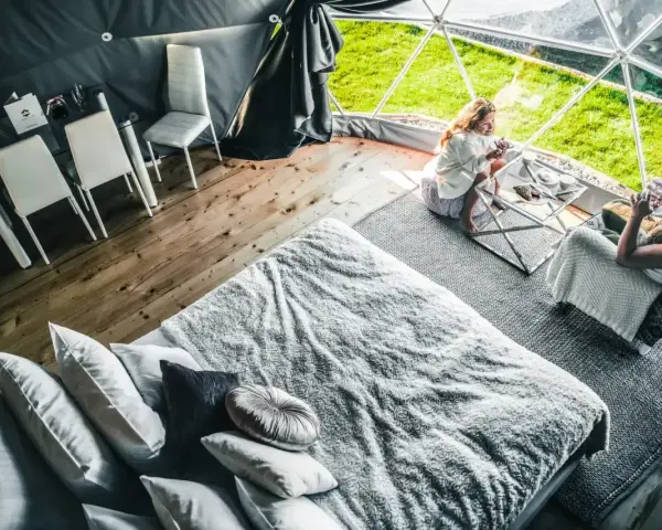 Dwie kobiety relaksują się w luksusowym namiocie. Przytulne wnętrze z wygodnym łóżkiem i stolikiem kawowym, idealne na camping w Zakopanem.