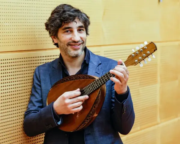 Mann mit Mandoline, die acht Saiten hat, lächelt.