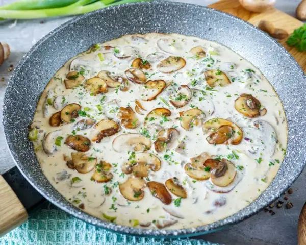 Cremige Champignon Rahmsauce in einer Pfanne, garniert mit frischer Petersilie. Ein köstliches Gericht, das zum Genießen einlädt.