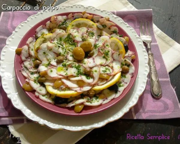 Carpaccio di polpo fresco, guarnito con olive, capperi e fette di limone, un piatto estivo da gustare.