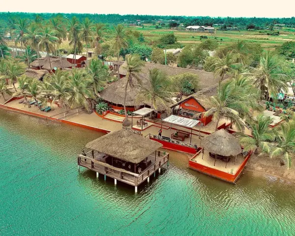 Rajskie wakacje w Ghanie: tropikalny kurort z palmami, plażą i domkami na wodzie.