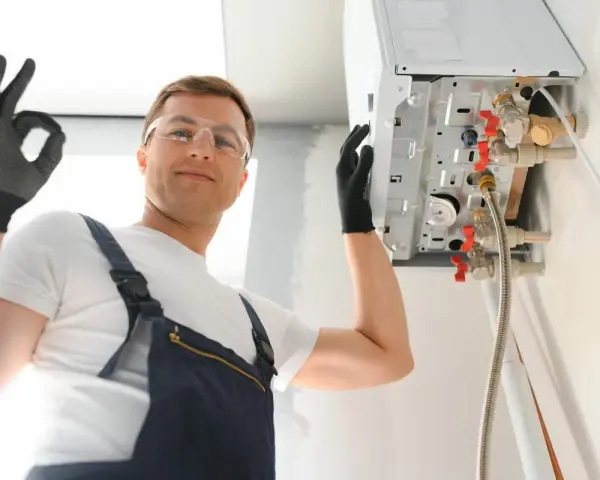 Installazione caldaia a condensazione risparmio energetico. L'installatore fa il segno OK.