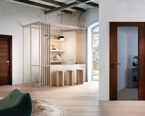 Porta in legno wenge colore, con maniglia in metallo, in un ambiente moderno con cucina a vista e pouf verde.