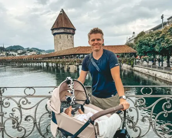 Szczęśliwy ojciec z niemowlakiem w wózku na moście, idealne miejsce, gdzie na wakacje z niemowlakiem.