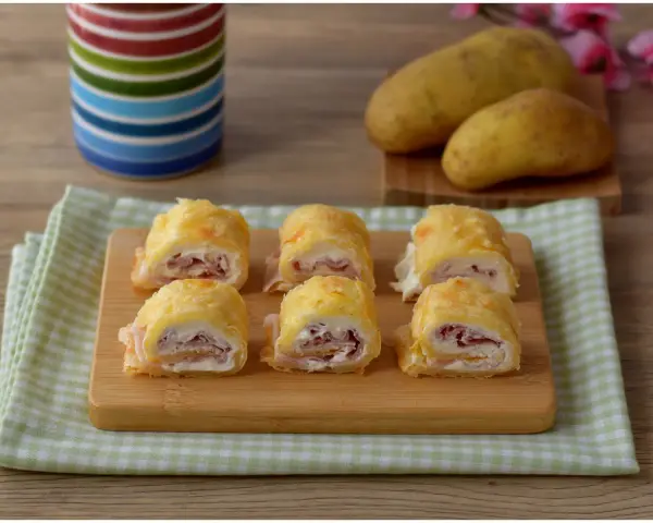 Sei rotoli di patate ripieni di prosciutto e formaggio cremoso, pronti per essere gustati.