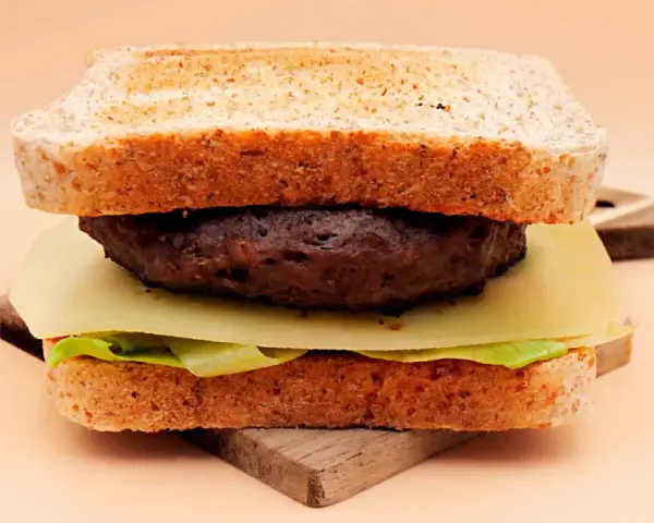 Burger z wołowiny, serem, sałatą i tostami na desce.
