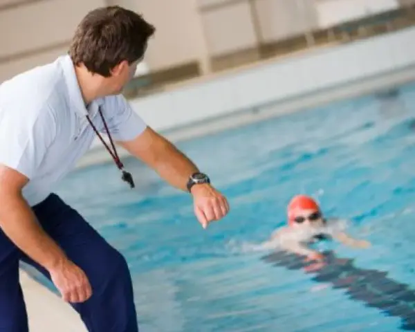 Entraîneur surveillant un nageur, peut-être pour un certificat de natation pour colonie.