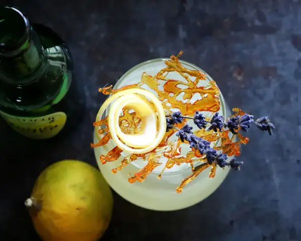 Erfrischender Drink mit Zitronenzeste, Karamell und Lavendel. Die bergamotte verwendung in Cocktails ist ein Genuss.