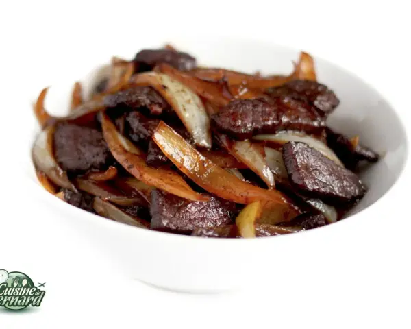 Un délicieux sauté de bœuf aux oignons caramélisés, servi dans un bol blanc. Un plat savoureux et réconfortant.